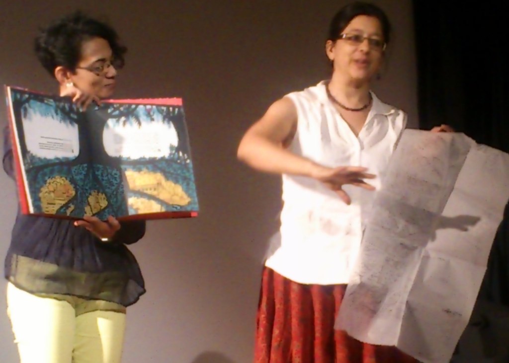 Karthika Nair and Anita Roy hold up the book and the first drafts of the illustrations during the presentation.